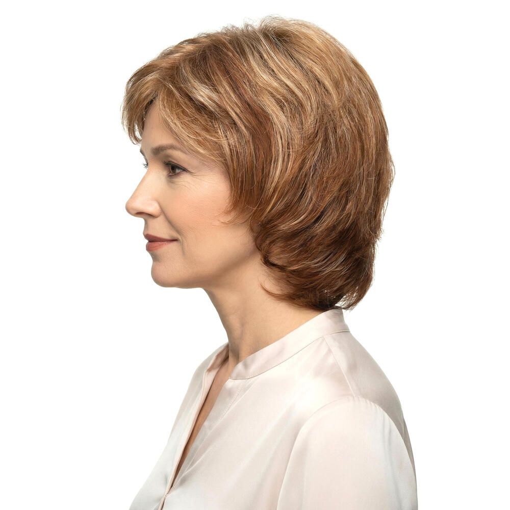 Frau mit Perücke, blond-braune Haare, Seitenansicht. Hellbraune Strähnen, schulterlange Frisur. Trägt eine helle Bluse.