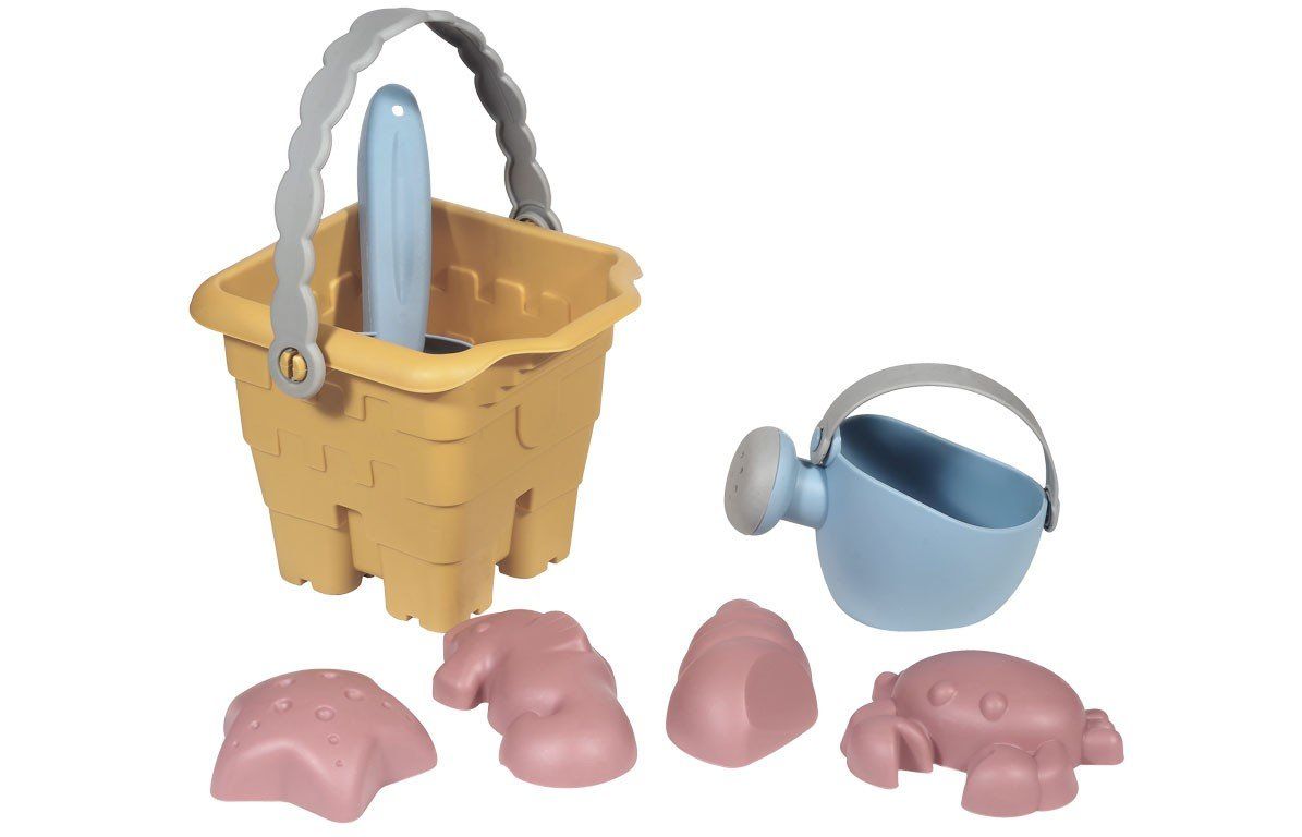 Gelber Eimer mit Griff, blaue Gießkanne, Schaufel und rosa Formen. Sandspielzeug auf weißem Hintergrund.