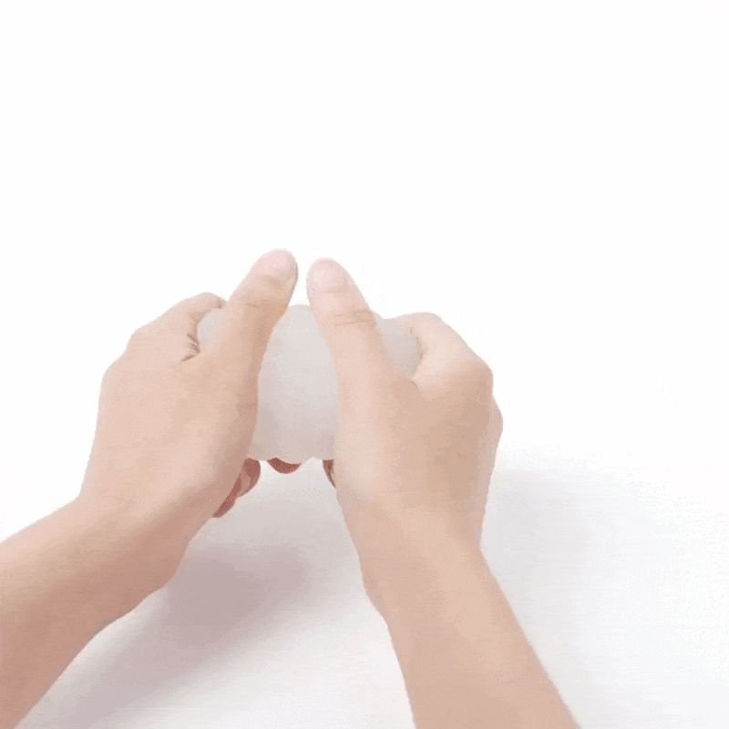 Hände halten ein weißes, wellenförmiges Objekt. Der Hintergrund ist weiß.