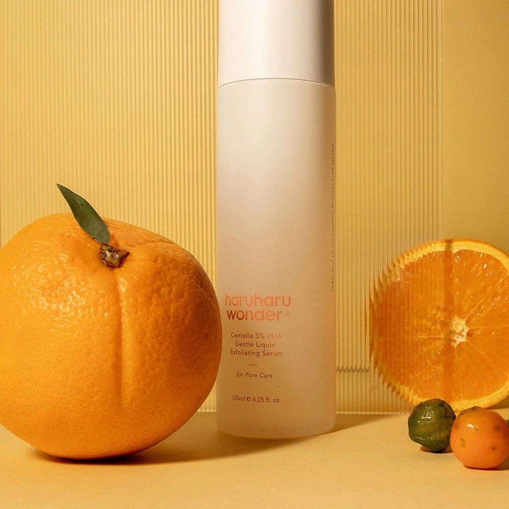 Produktflasche neben Orange und halber Orange. Aufschrift: haruharu wonder, Centella 3% PHA Gentle Liquid Exfoliating Serum.