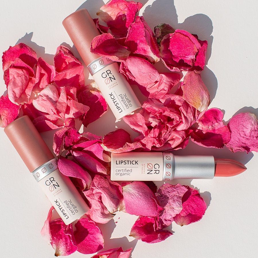 Drei Lippenstifte auf Rosenblättern. Aufschrift: GRN, Lipstick, certified organic. Rosa Lippenstifte mit rosafarbenen Deckeln.