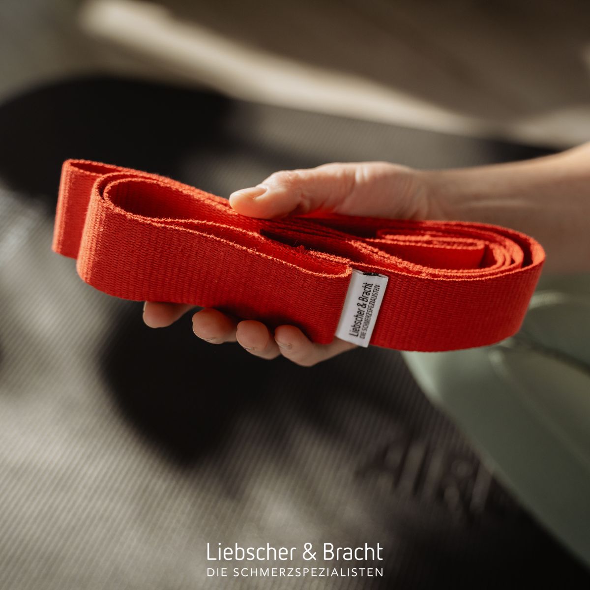 Hand hält gefaltete rote Übungsschlaufe mit Etikett.