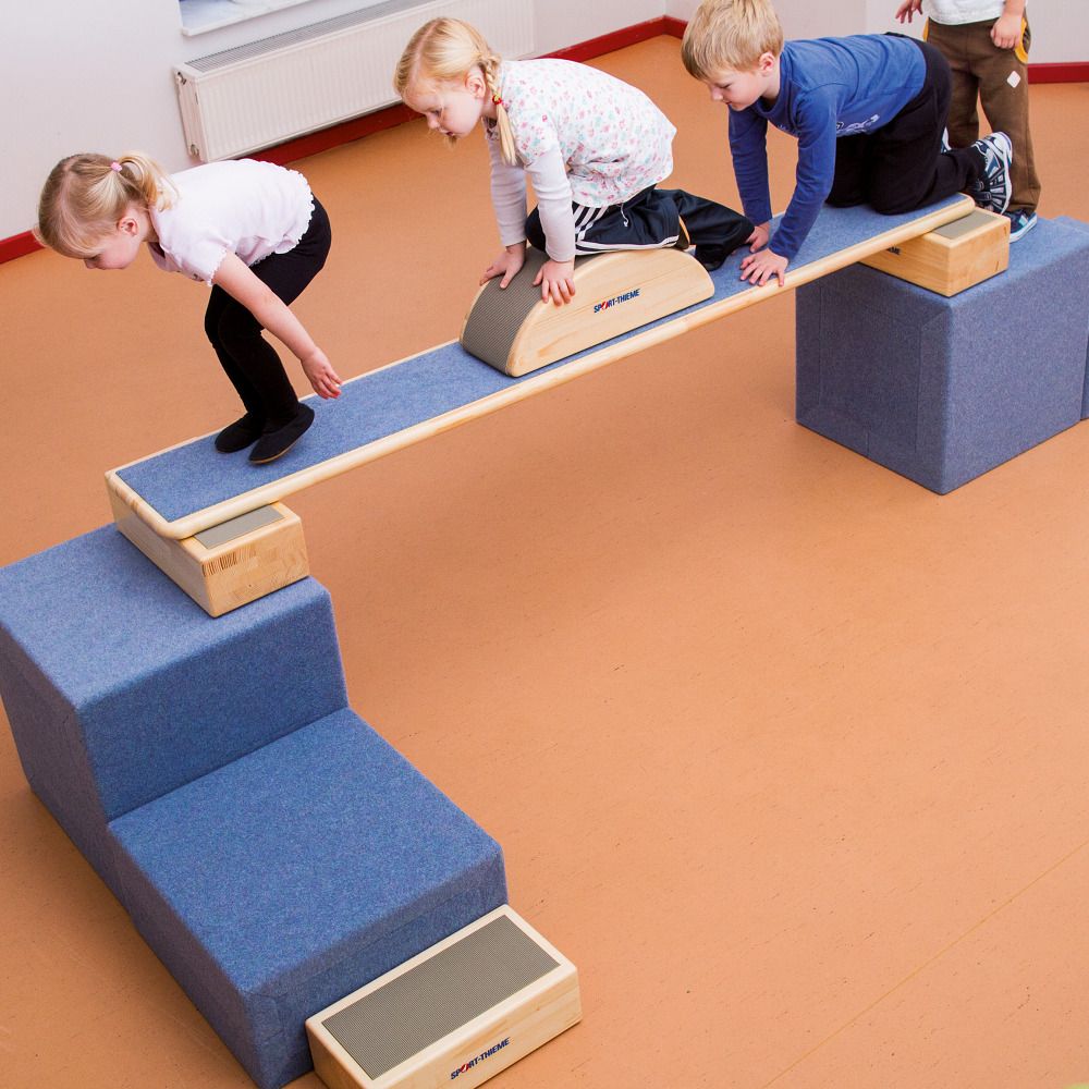 Kinder balancieren auf Elementen. Blaue und Holz-Elemente. Sport-Thieme Logo sichtbar.