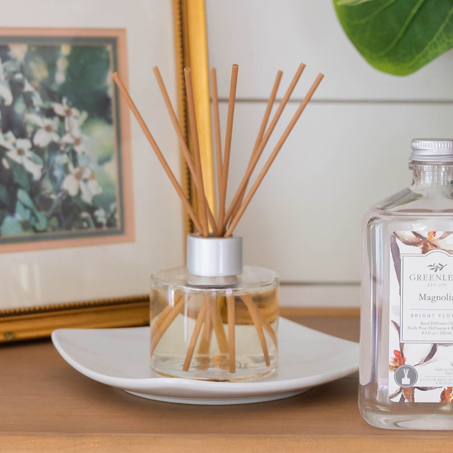 Greenleaf Magnolia Reed Diffuser in Glasflasche mit Holzstäbchen auf einem Teller.