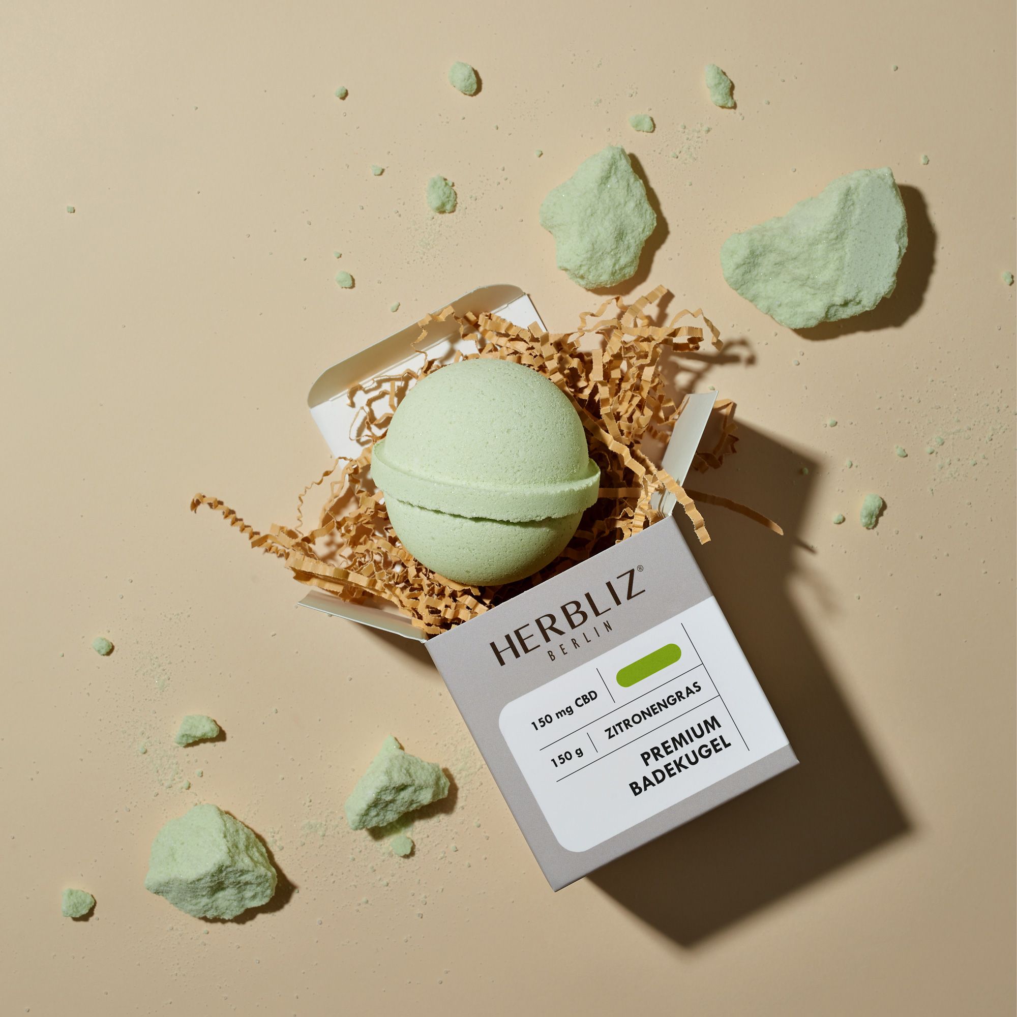Geöffnete Verpackung mit hellgrüner Badekugel und Dekoration. Logo und Produktname auf der Verpackung. 150mg CBD.