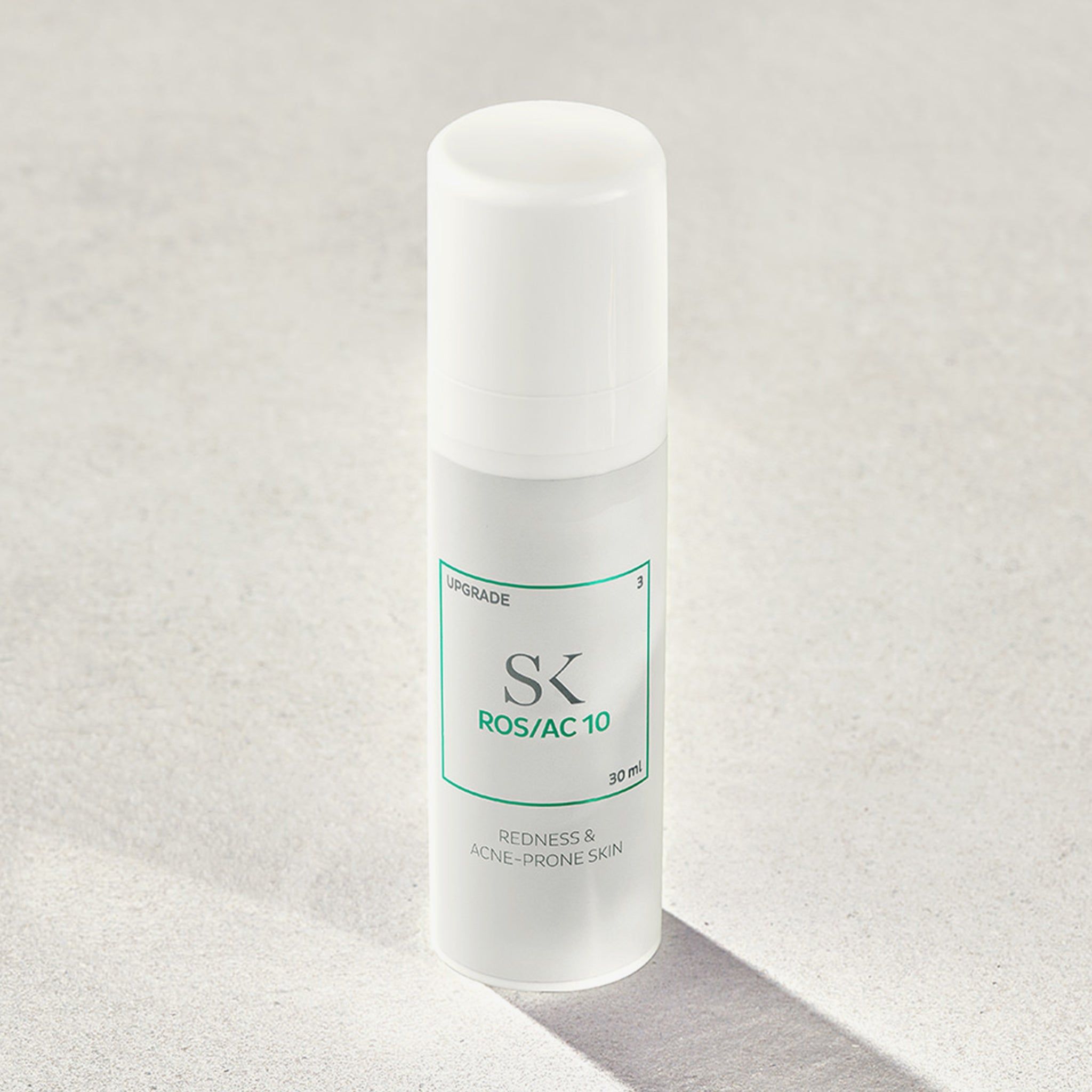 Weiße Flasche mit grünem Etikett. Aufschrift: SK ROS/AC 10, Redness & Acne-Prone Skin. 30 ml.