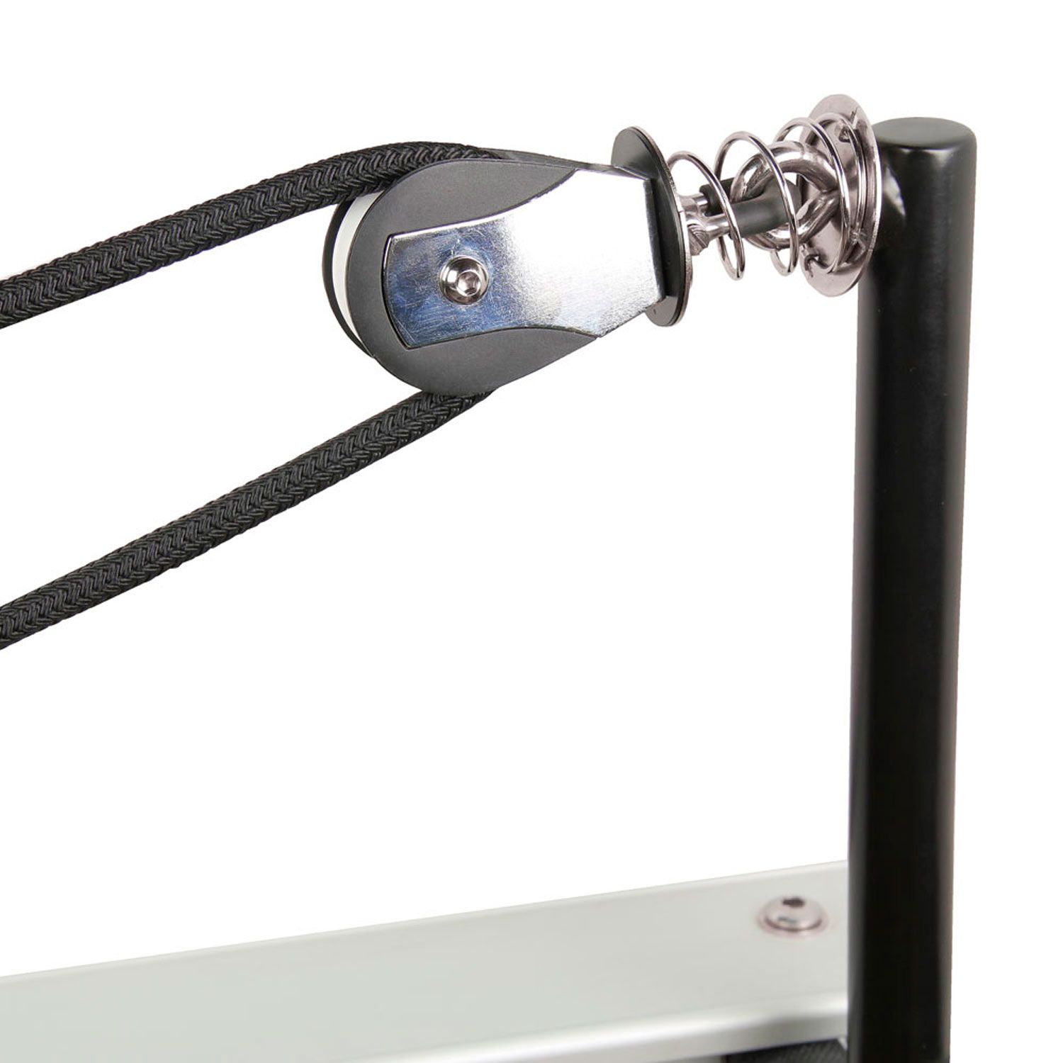 Schwarzes Seil an Umlenkrolle mit Feder und Metallhalterung. Teil eines Pilates-Geräts.