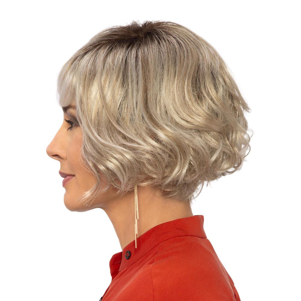 Perücke Biarritz von DELUXE. Blond gewellt, mit Pony. Frau mit roter Bluse. Profilansicht.
