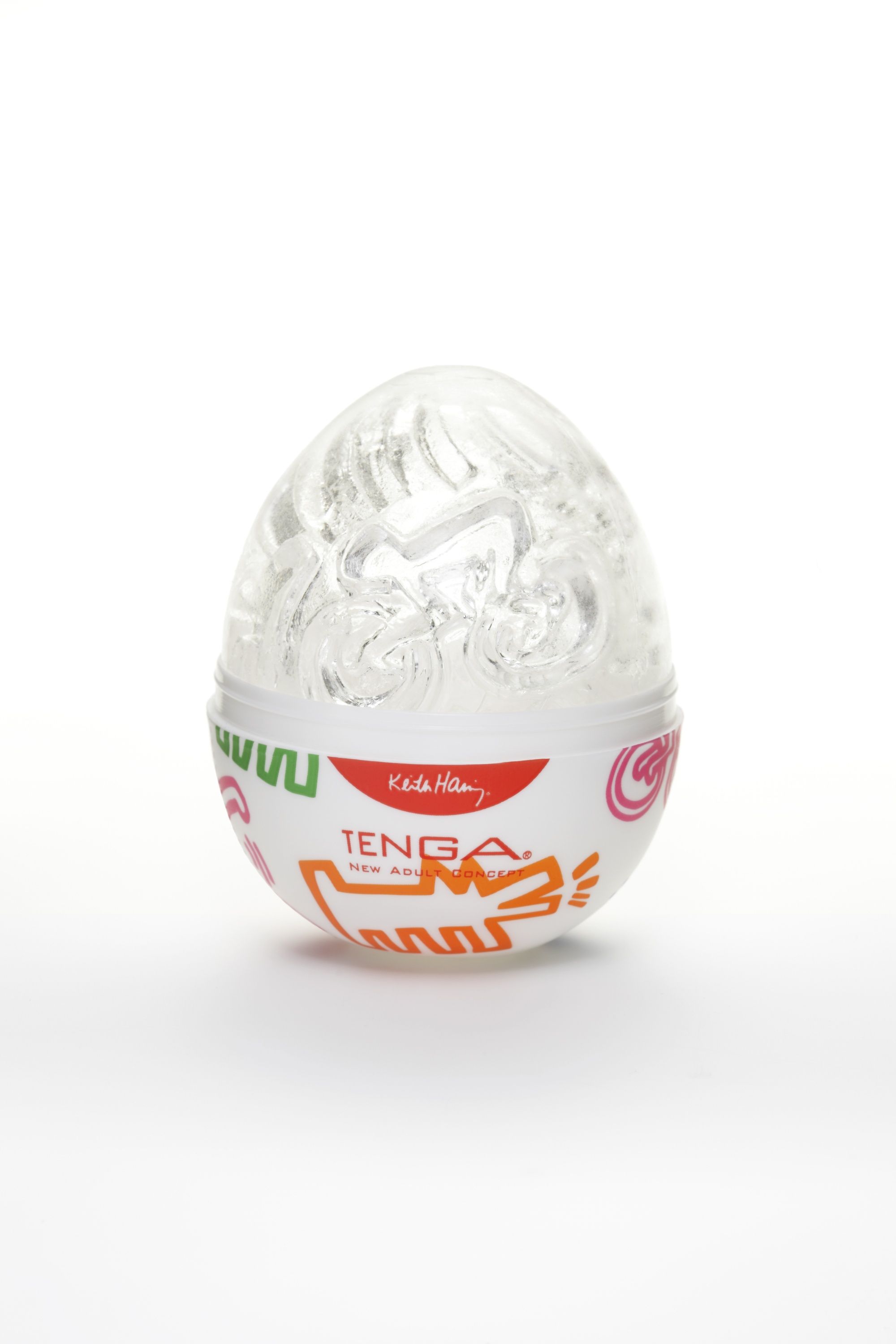 Eiförmiges Produkt in Verpackung. Weißer Behälter mit farbigen Mustern und rotem Aufkleber mit Text. TENGA-Logo sichtbar.
