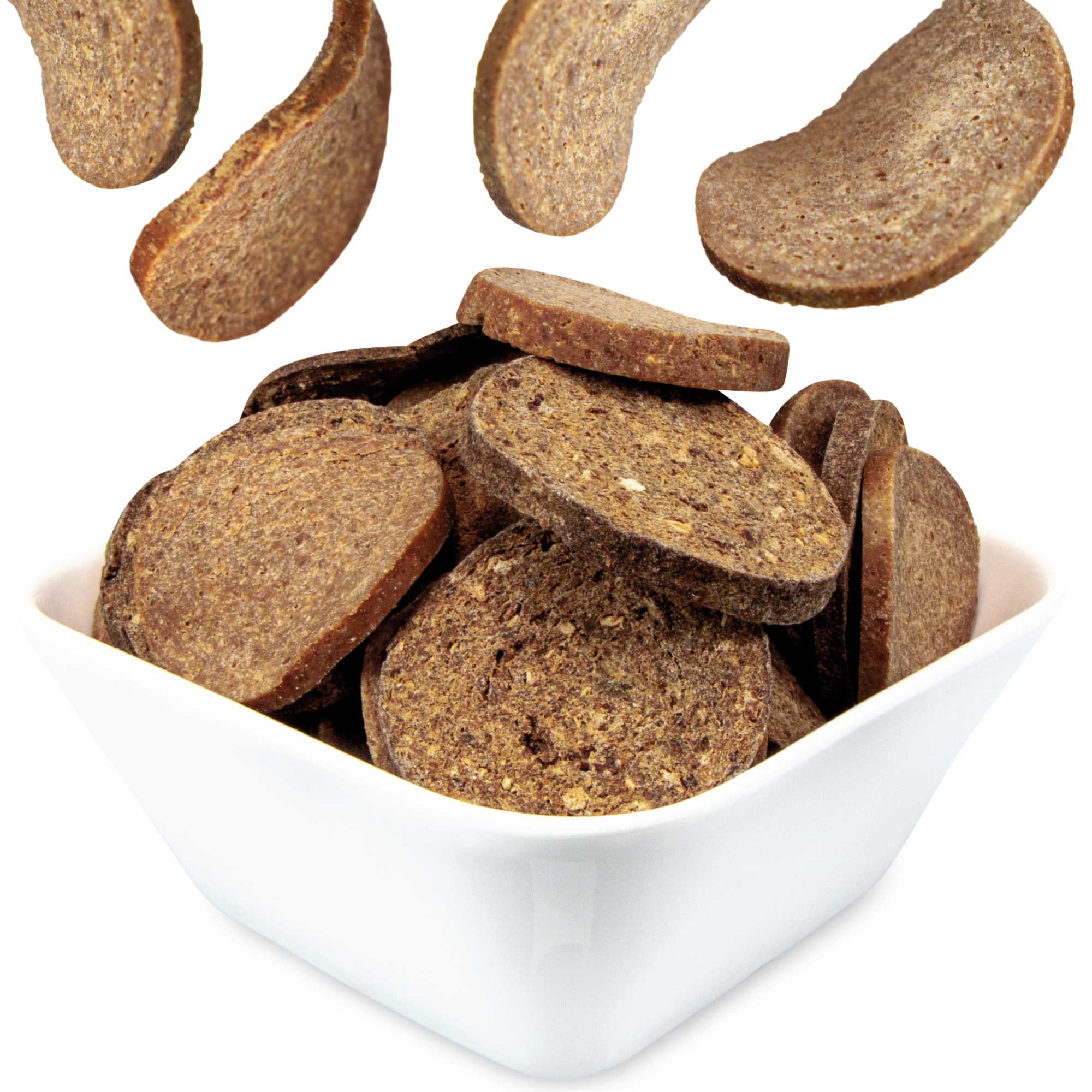 Chipies Lamm, krosse Fleisch-Chips-Taler für Hunde in einer weißen Schüssel. Einige Chips fallen.