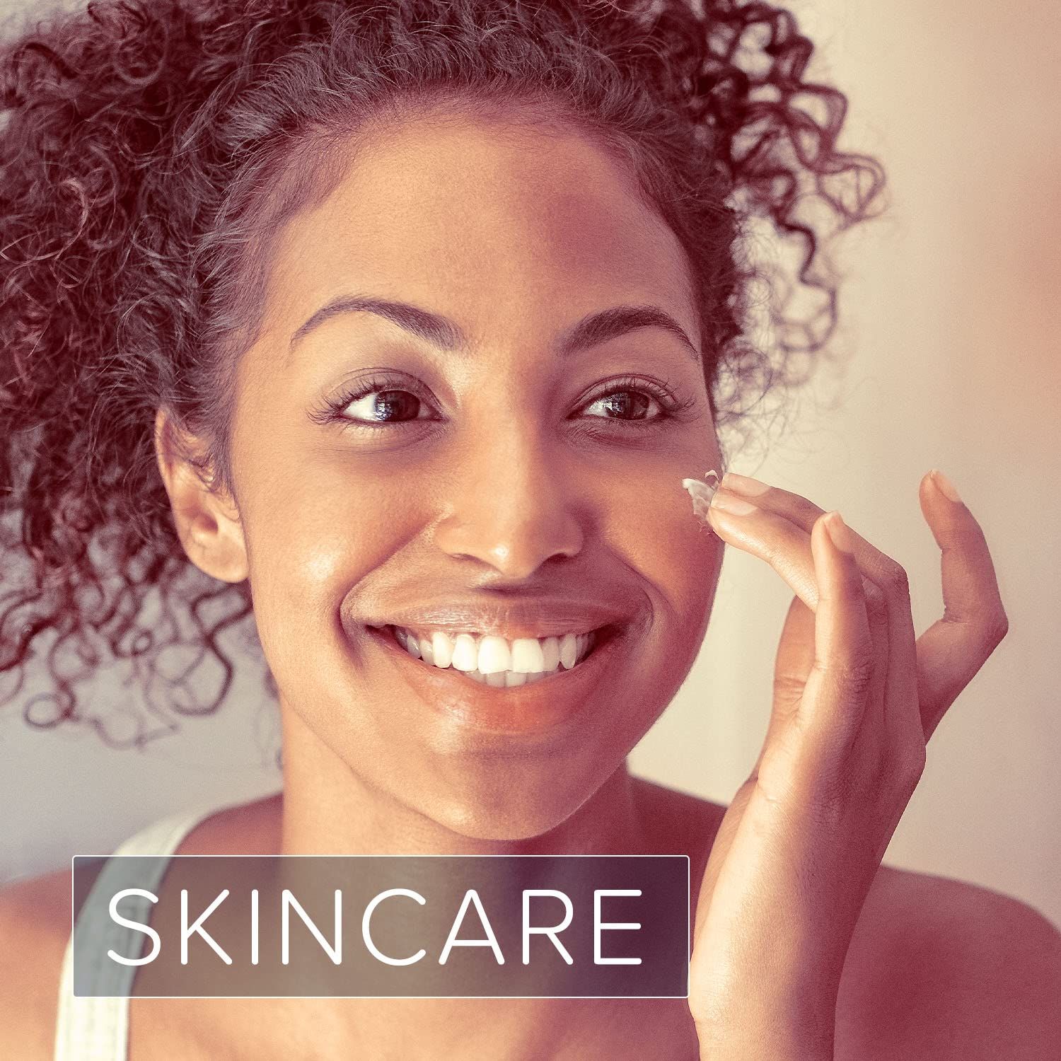 Frau trägt Creme auf ihr Gesicht auf. Aufschrift: SKINCARE.