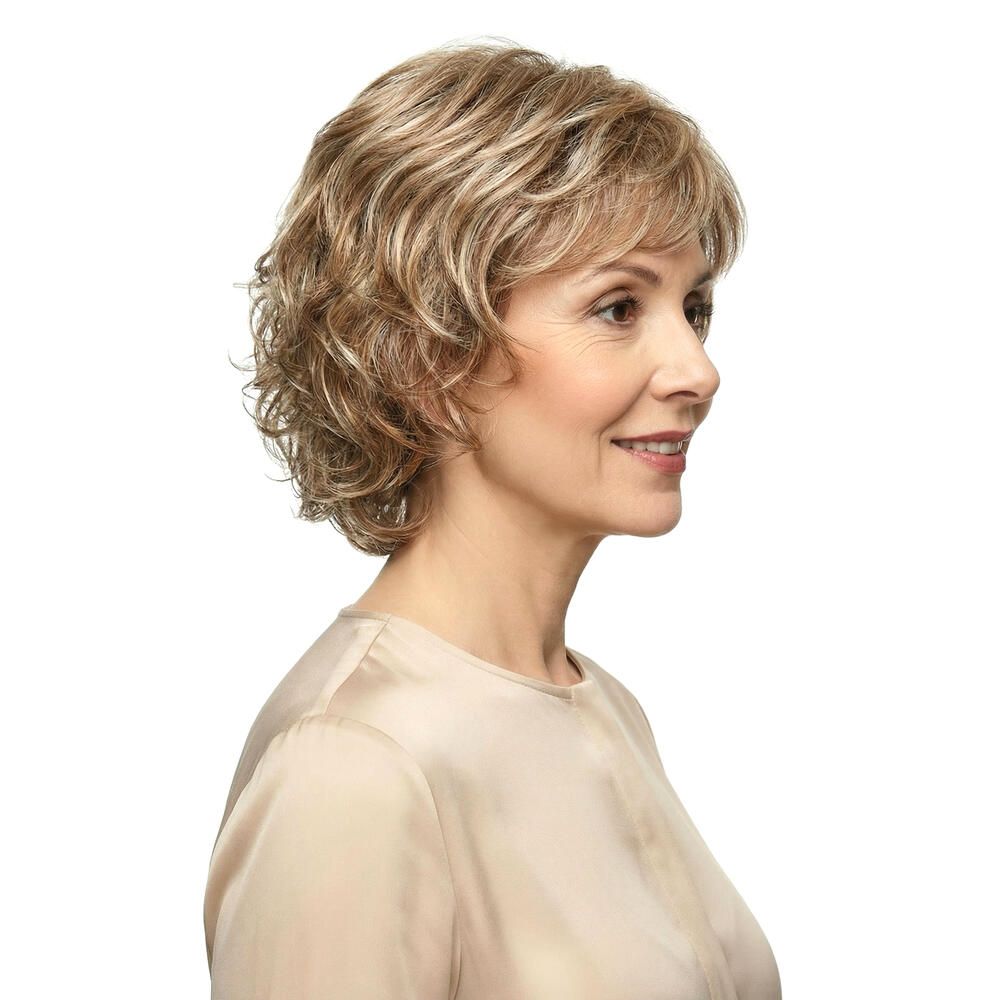 Perücke mit gewelltem, blond-braunem Haar. Frau mit hellem Oberteil, Seitenansicht, vor weißem Hintergrund.