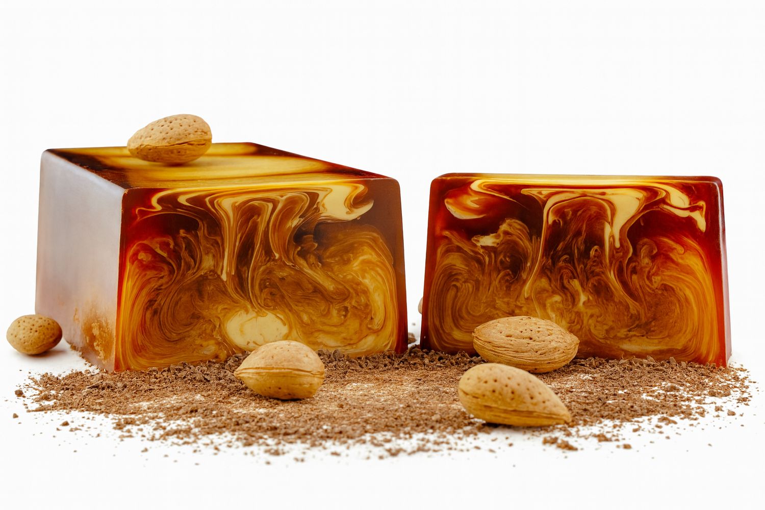 Zwei rechteckige Seifenstücke mit braunen Wirbeln. Mandeln und Schokoladenstückchen liegen daneben.