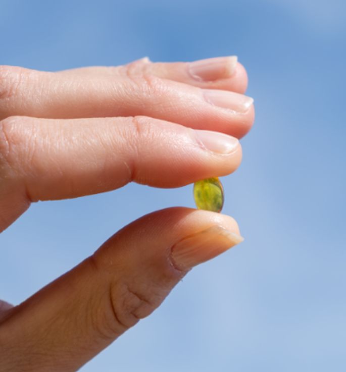 Finger hält eine Aavalabs Vitamin D3 Softgel-Kapsel.