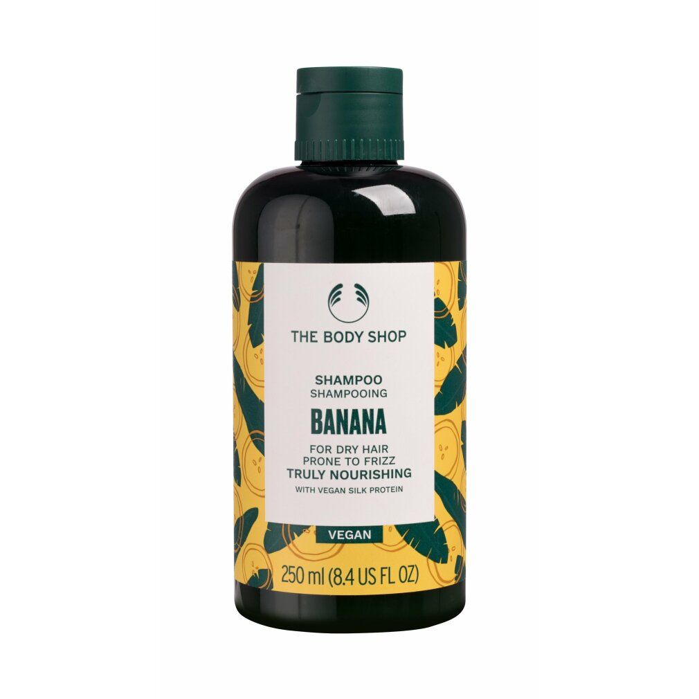 Dunkelgrüne Shampoo-Flasche mit gelbem Etikett und Bananenmuster. Aufschrift: The Body Shop Banana Shampoo, 250 ml.
