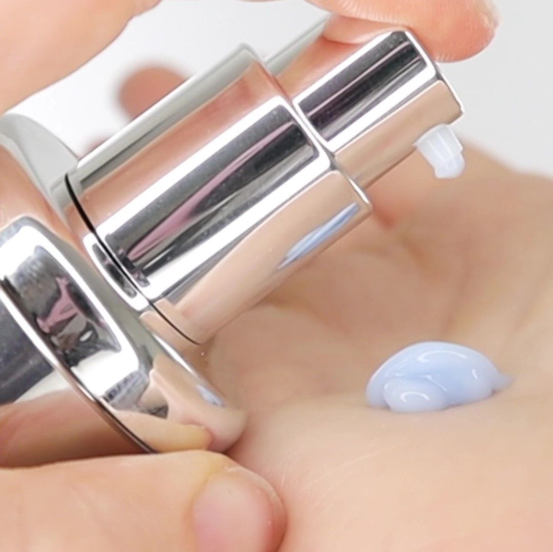 Nahaufnahme einer Hand, die eine kleine Menge blaues Serum aus einem Sprühkopf abgibt. Serum auf der Handfläche.