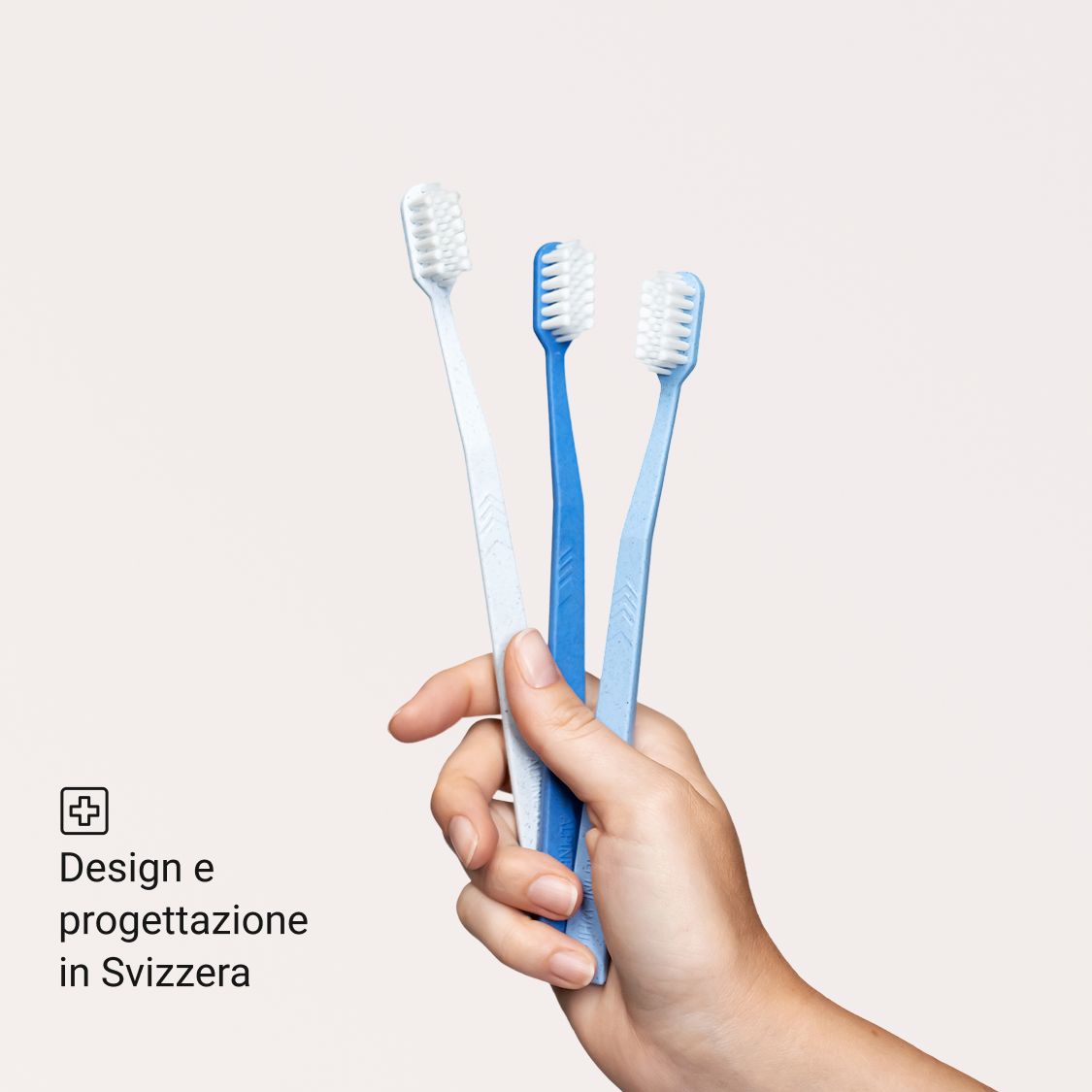 Tre spazzolini blu in diverse tonalità. Tenuti in una mano.