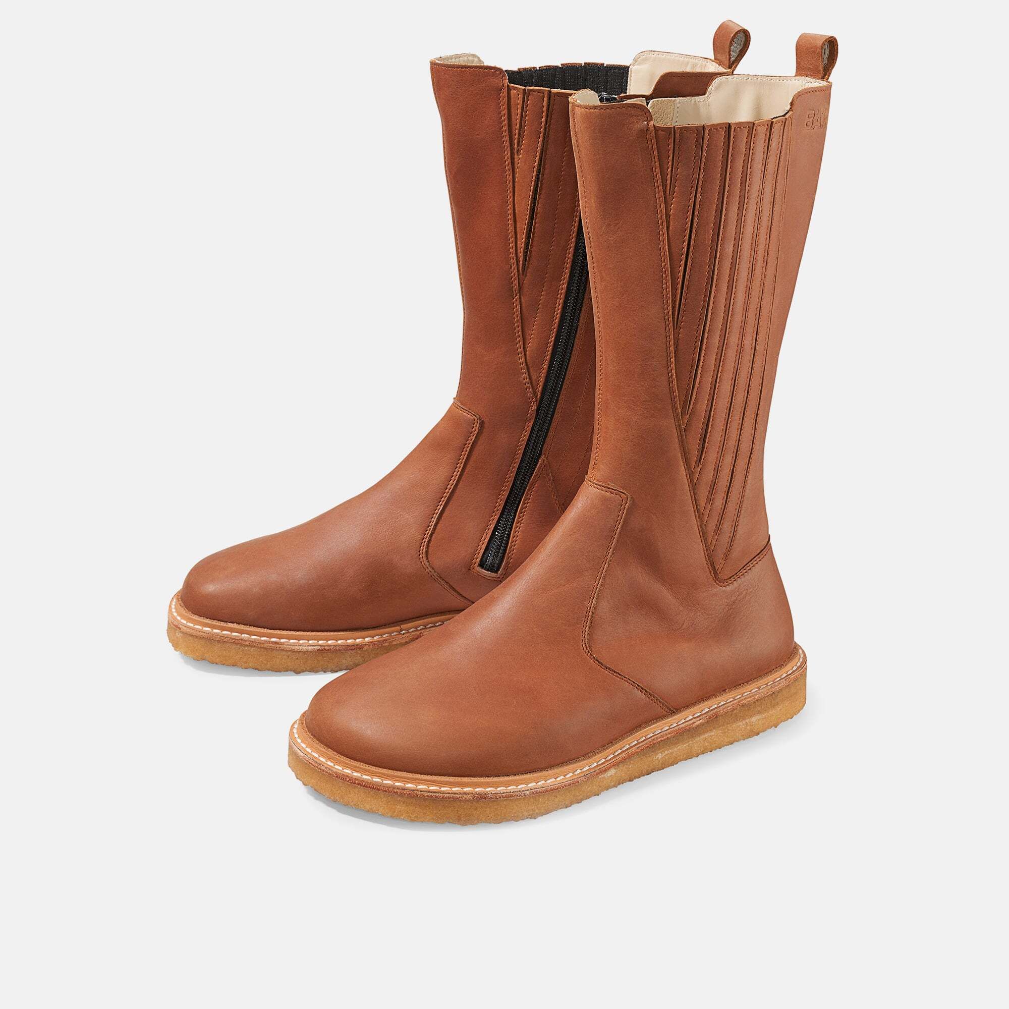 Braune Damenstiefel. Seitlicher Reißverschluss, breite Sohle. Zwei Stiefel nebeneinander, leicht schräg gestellt.