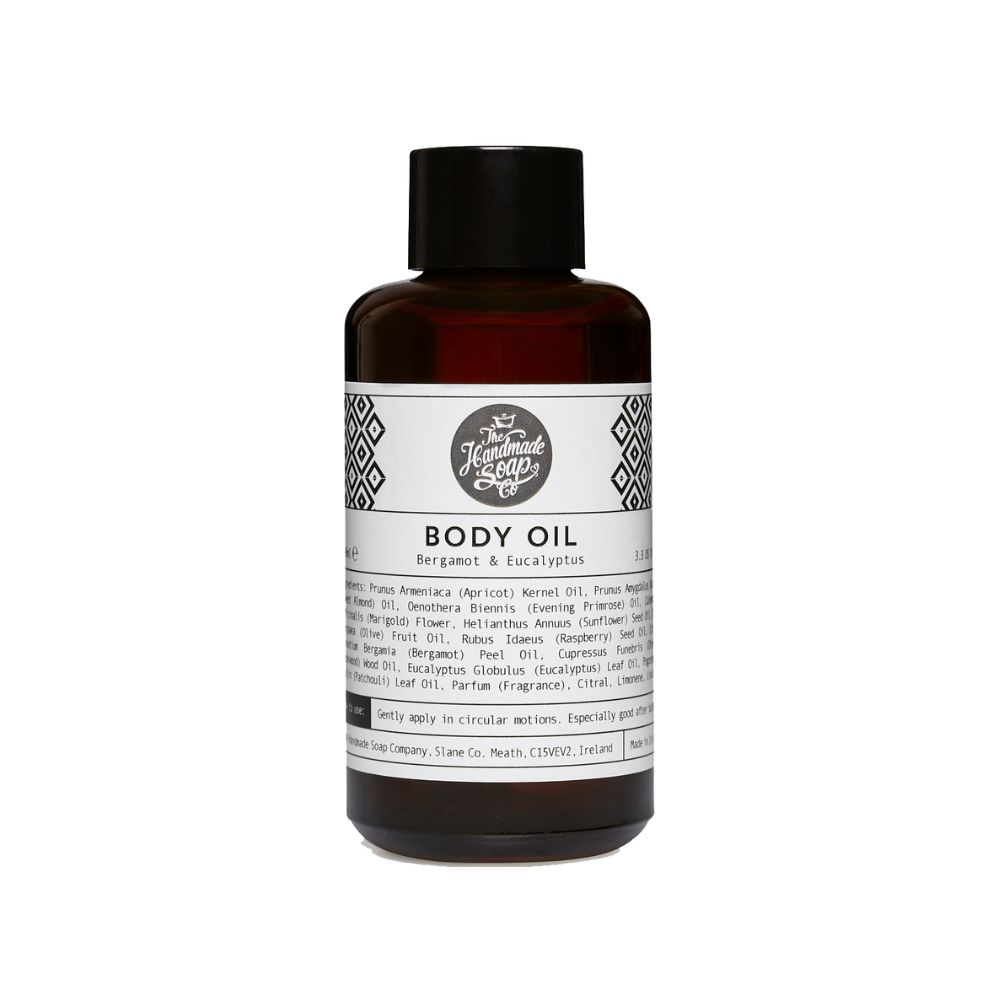 Braune Glasflasche mit schwarzem Deckel. Etikett mit Text: Body Oil, Bergamot & Eucalyptus. Logo: The Handmade Soap Company.