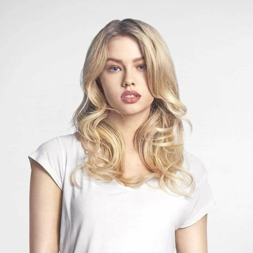 Porträt einer Frau mit blonden, gewellten Haaren. Sie trägt ein weißes T-Shirt.