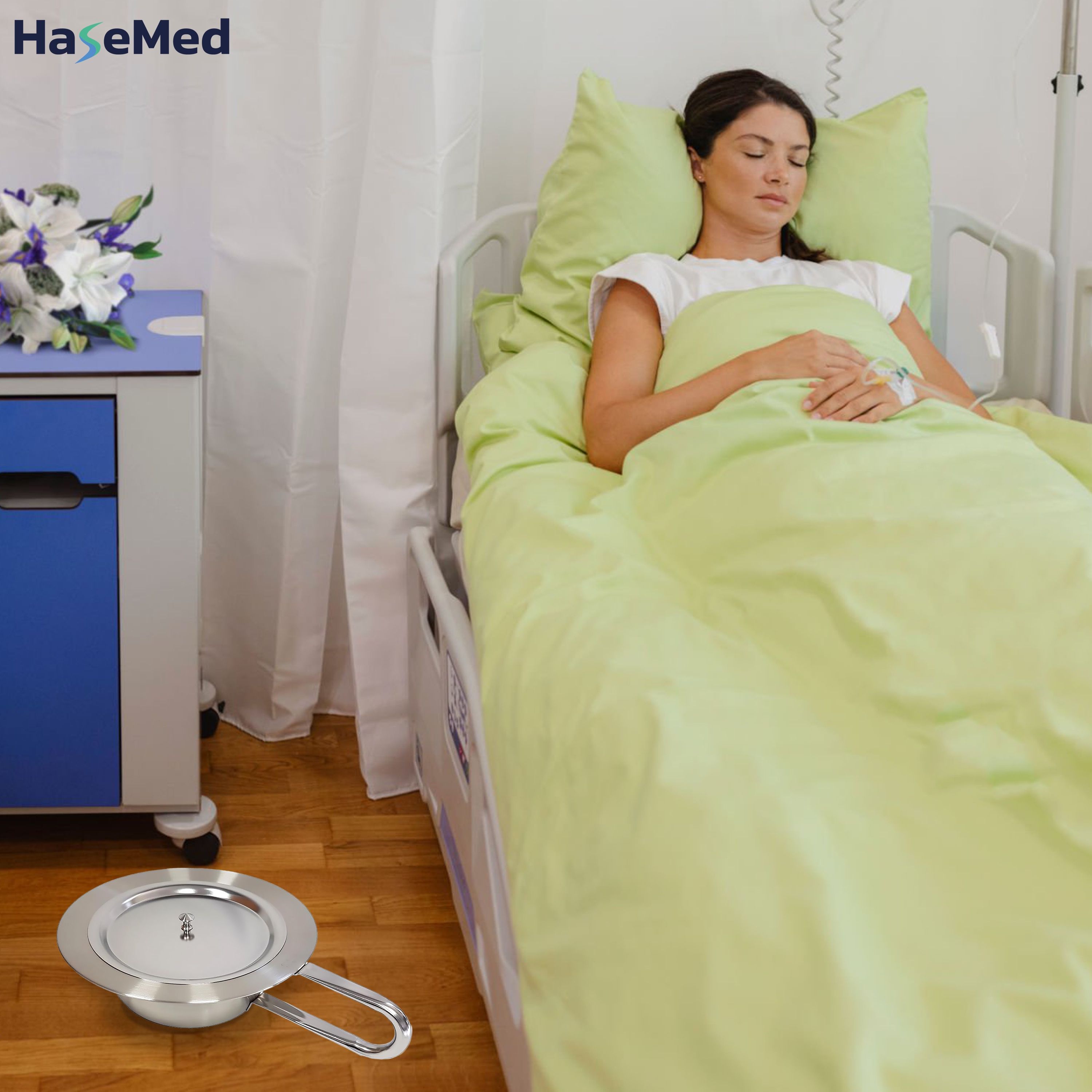Edelstahl-Steckbecken mit Deckel auf einem Nachttisch neben einem Patientenbett. Marke HaseMed.