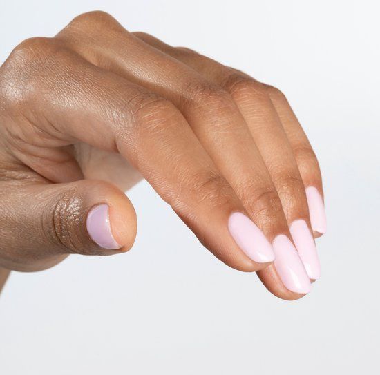 Hand mit hellrosa lackierten, oval geformten Nägeln. Hautton mittelbraun. Hintergrund weiß.