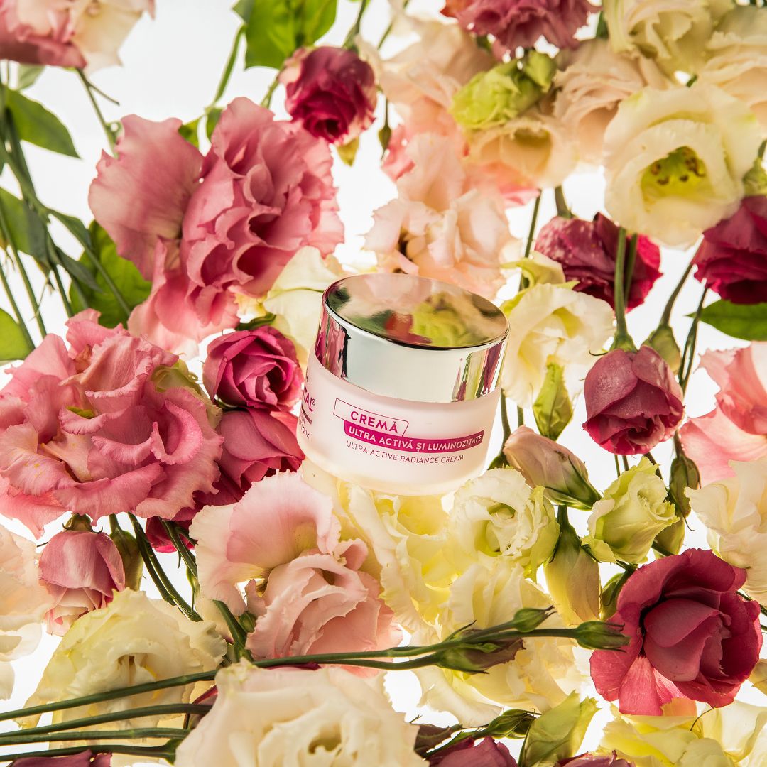 Creme-Tiegel inmitten von Blumen. Aufschrift: Crema Ultra Active. Hintergrund: Blumen.