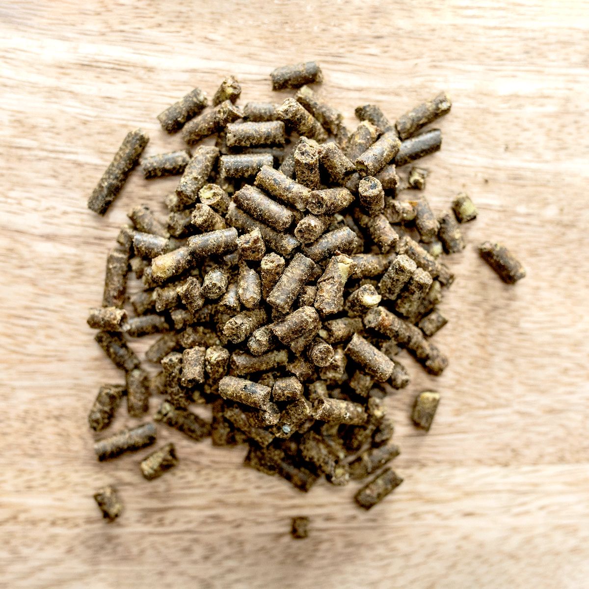 Haufen brauner Pellets auf Holzuntergrund. Draufsicht.