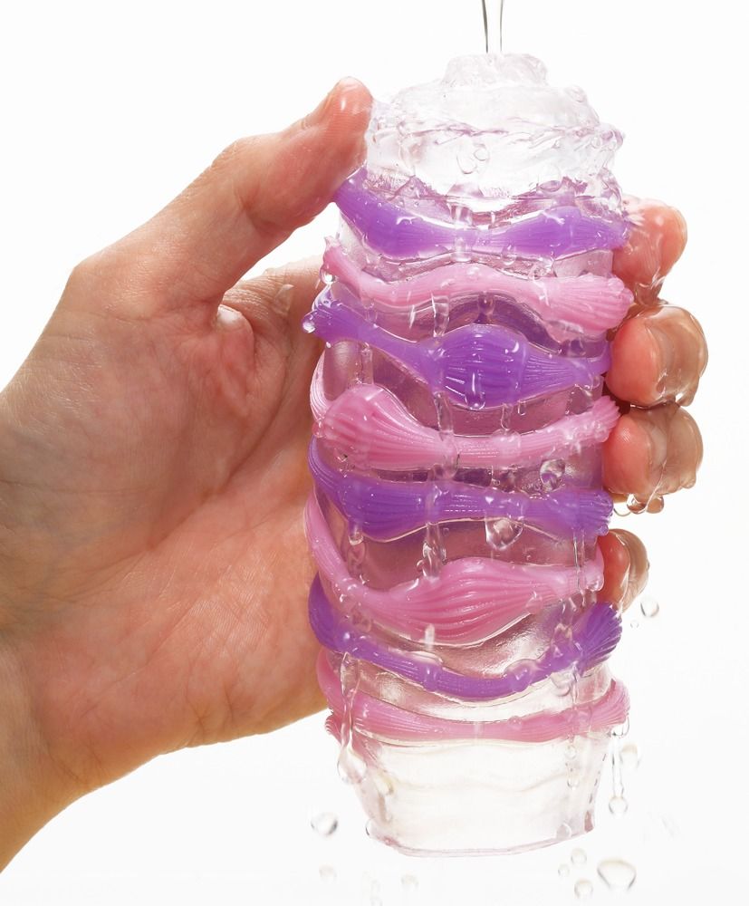 Hand hält einen transparenten TENGA ARTE Masturbator, Wasser fließt darüber. Lila und rosa Innenstruktur sichtbar.