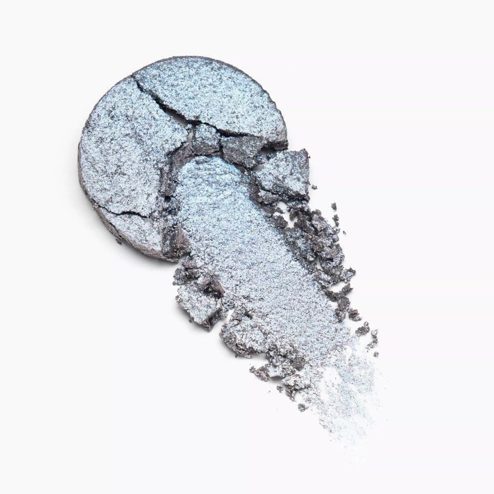 Zerbrochener, runder Lidschatten mit silberner Farbe und einem Farbabstrich. Keine Marke oder Produktname sichtbar.