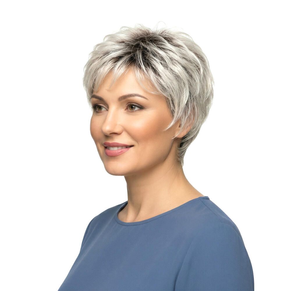 Kurzhaarperücke mit grau-melierten Strähnen. Die Frau trägt ein blaues Oberteil. Seitenansicht, lächelnd.