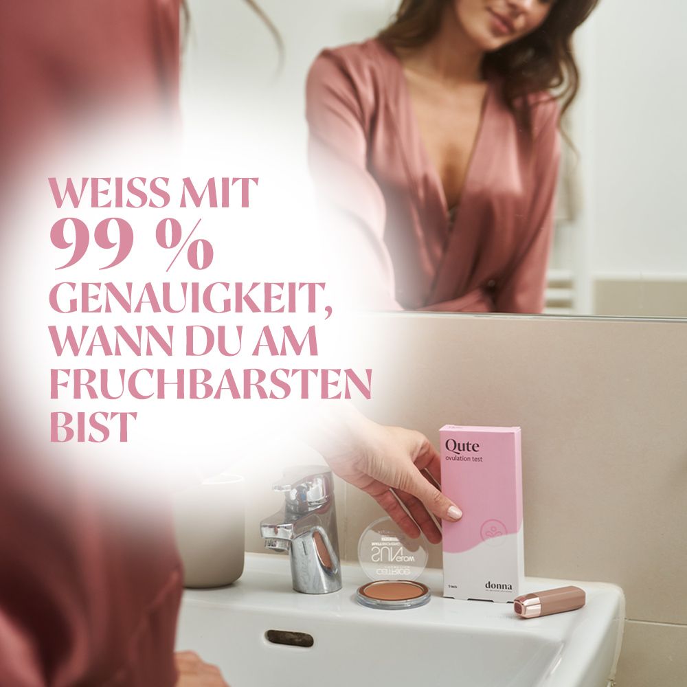 Eine Frau hält eine Qute Ovulationstest-Packung. Rosa Verpackung mit weißem Text. Aufschrift: Qute Ovulationstest.