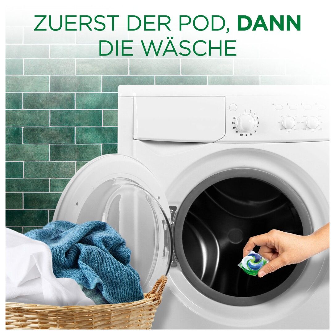 Eine Hand legt einen Ariel All-in-1 Pod in eine Waschmaschine. Im Hintergrund Wäsche in einem Korb.