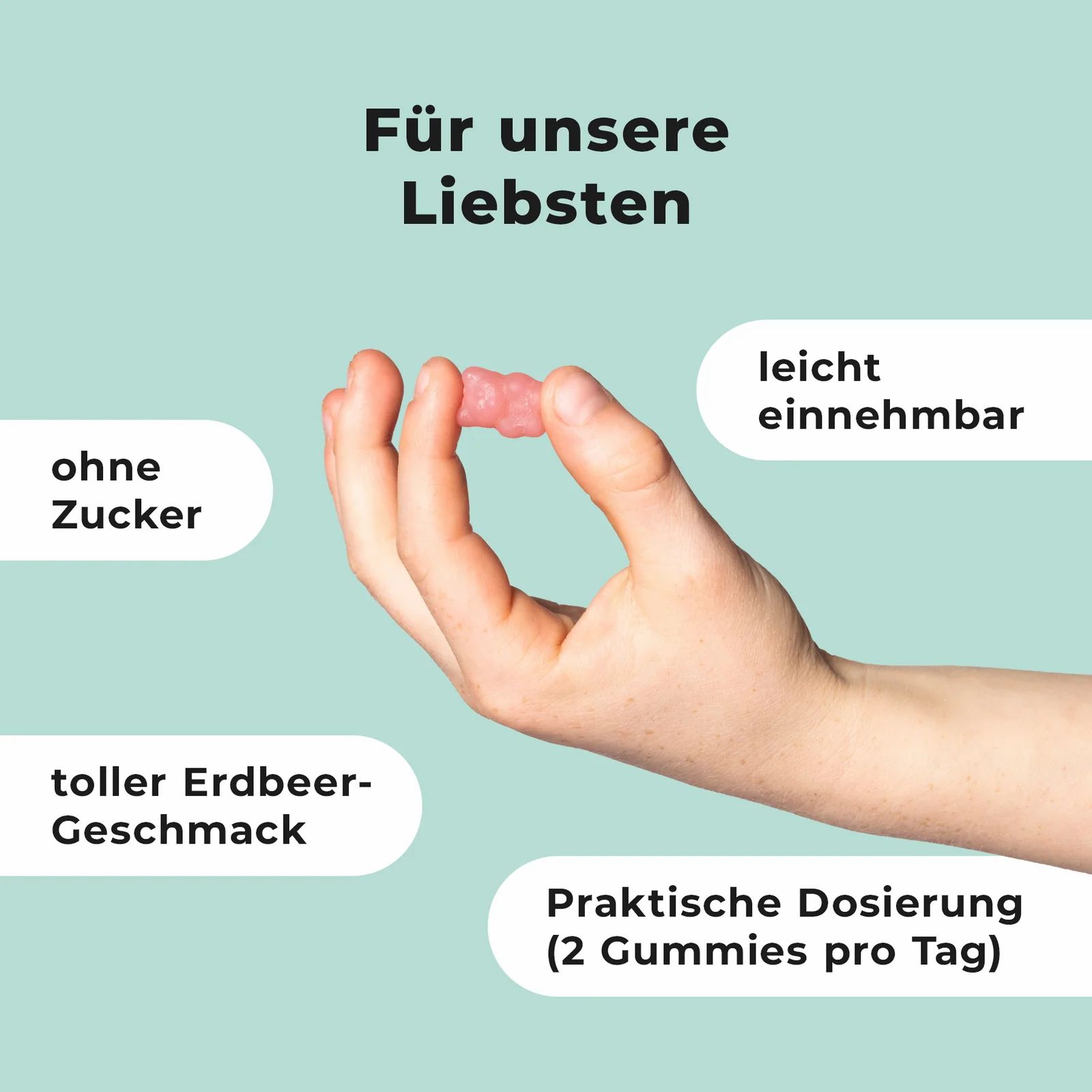 Hand hält ein rosa Gummibärchen. Ohne Zucker, leichter Erdbeergeschmack. Praktische Dosierung: 2 Gummis pro Tag.