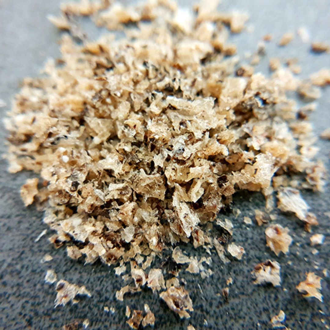 Nahaufnahme von QCHEFS Zahnputzflocken. Die Flocken sind körnig und von hell- bis dunkelbrauner Farbe.