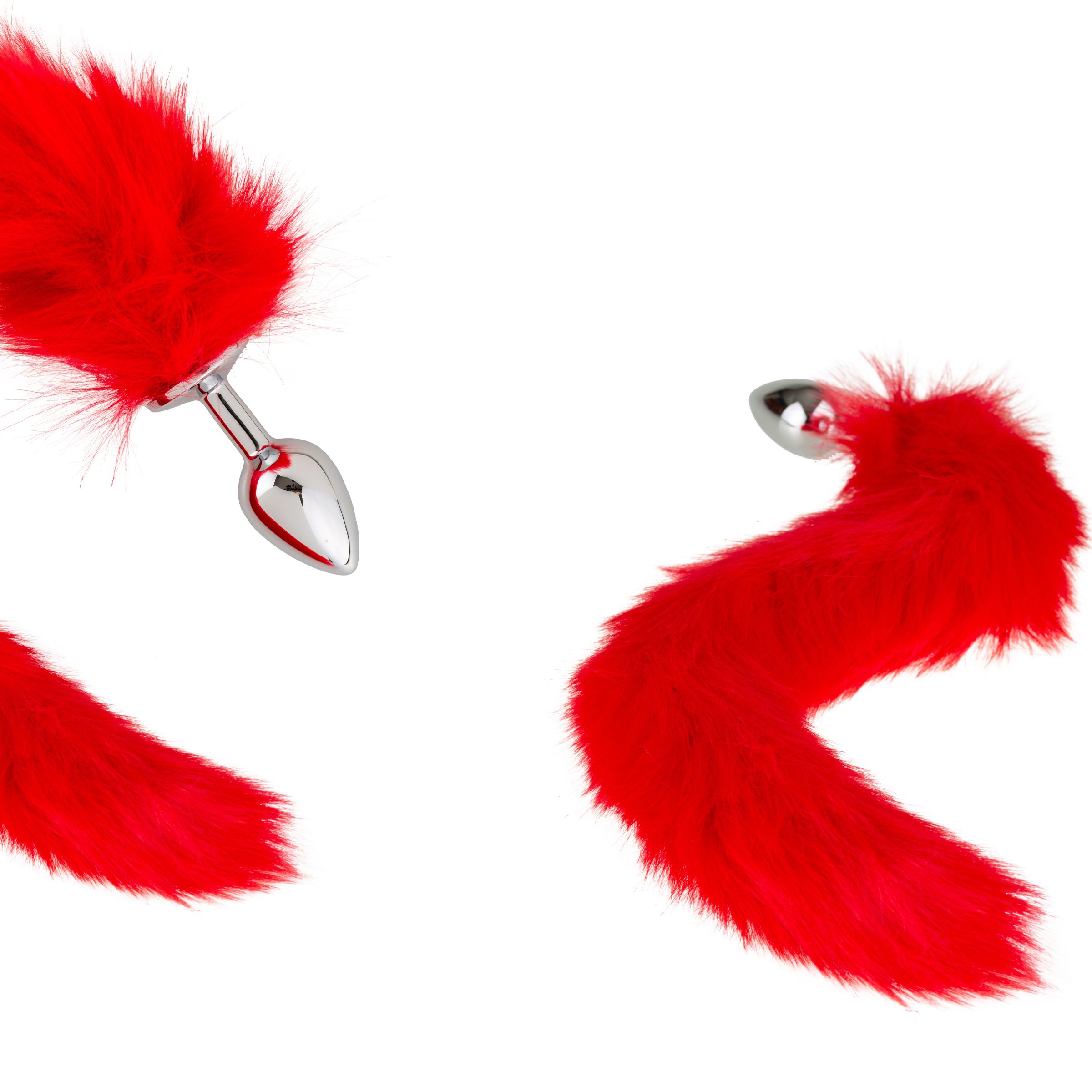 Drei rote, pelzige Schwänze mit Metallbasis, auf weißem Hintergrund. Zwei Schwänze sind teilweise sichtbar.