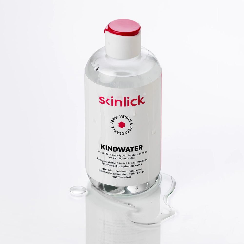 Flasche SKINLICK Kindwater Mizellenwasser mit verschütteter Flüssigkeit. Transparente Flüssigkeit.
