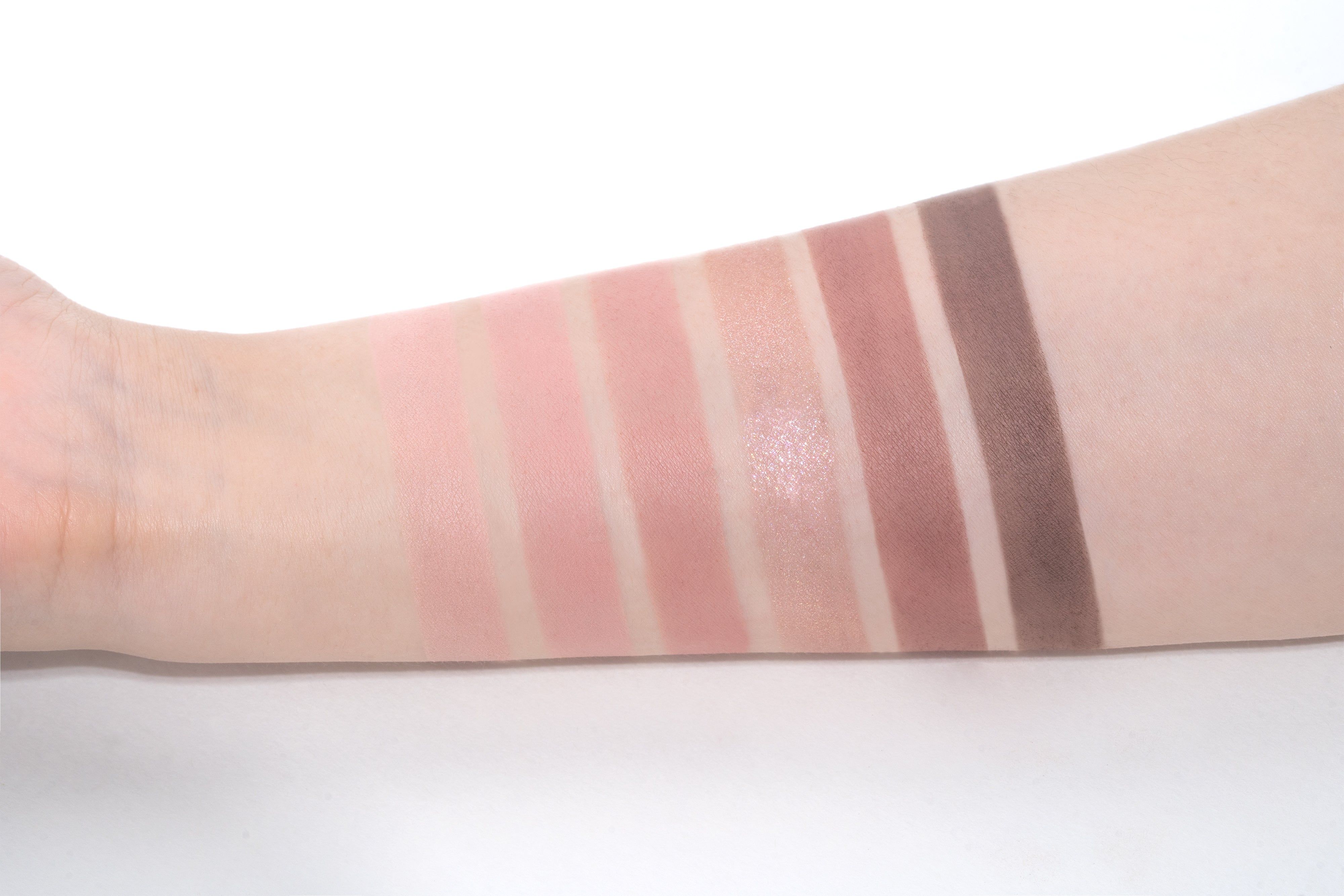 Arm mit sechs Lidschatten-Farben in rosa und braunen Tönen. Pudertextur.