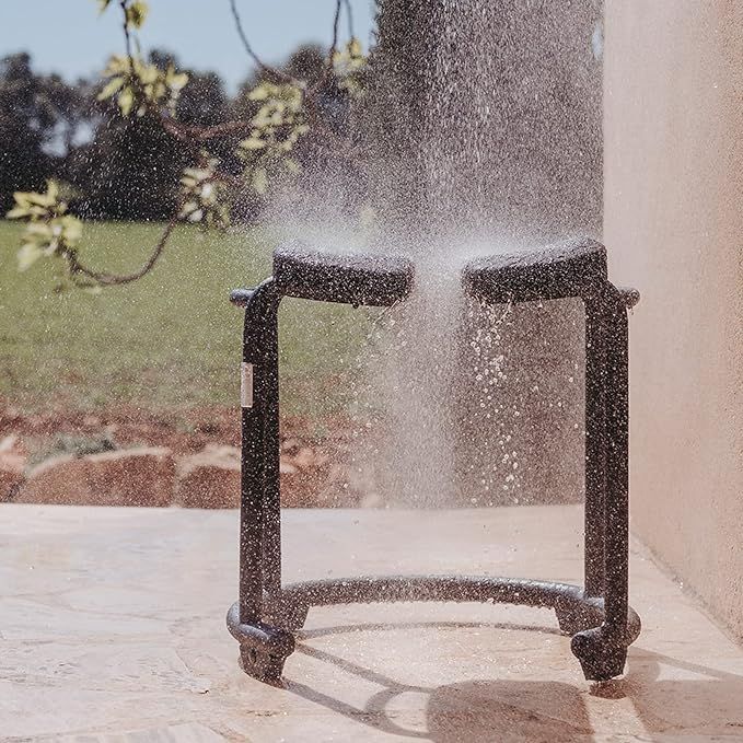 Duschhocker unter fließendem Wasser. Der Hocker hat zwei Sitze und einen grauen Rahmen. Wasser spritzt auf die Sitze.