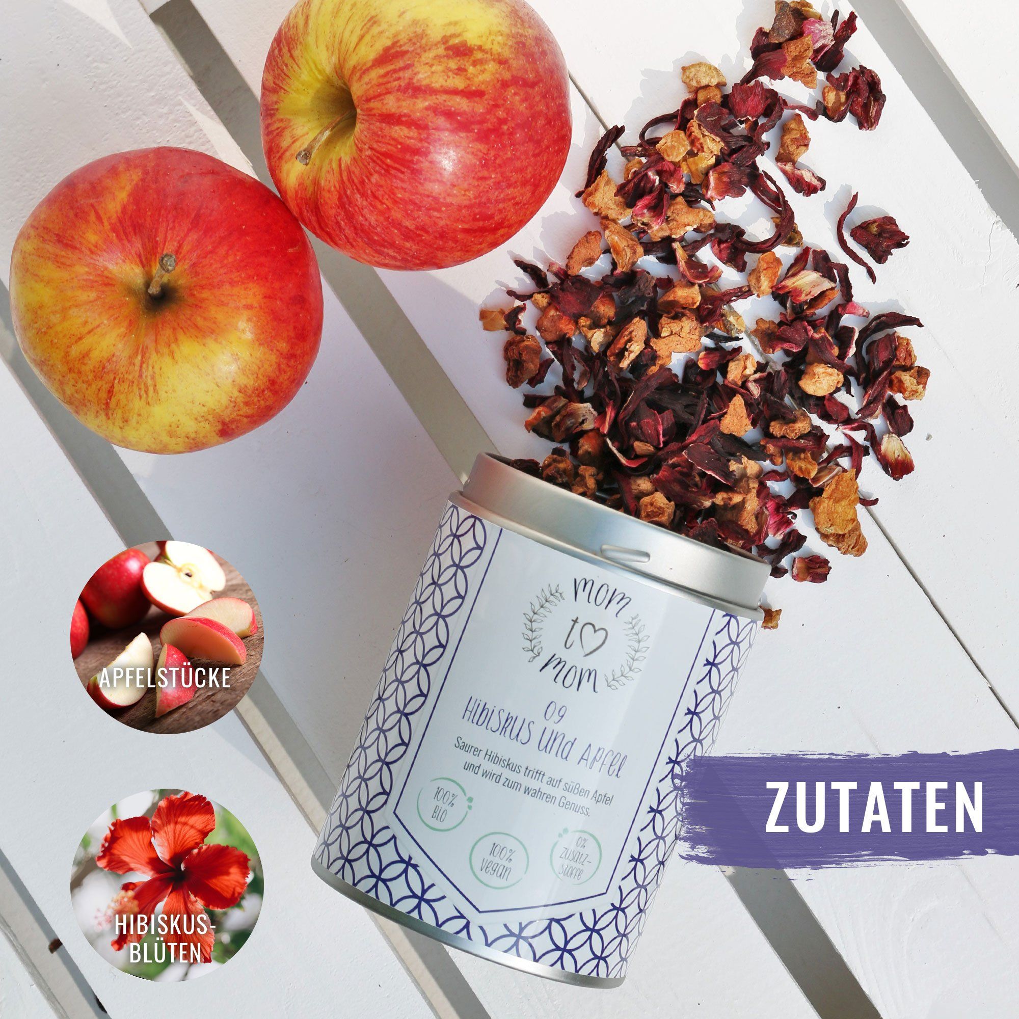 Teedose mit losem Tee, zwei Äpfel und Zutaten-Grafiken. Dose mit Aufschrift 'mom to mom' und 'Hibiskus & Apfel'.
