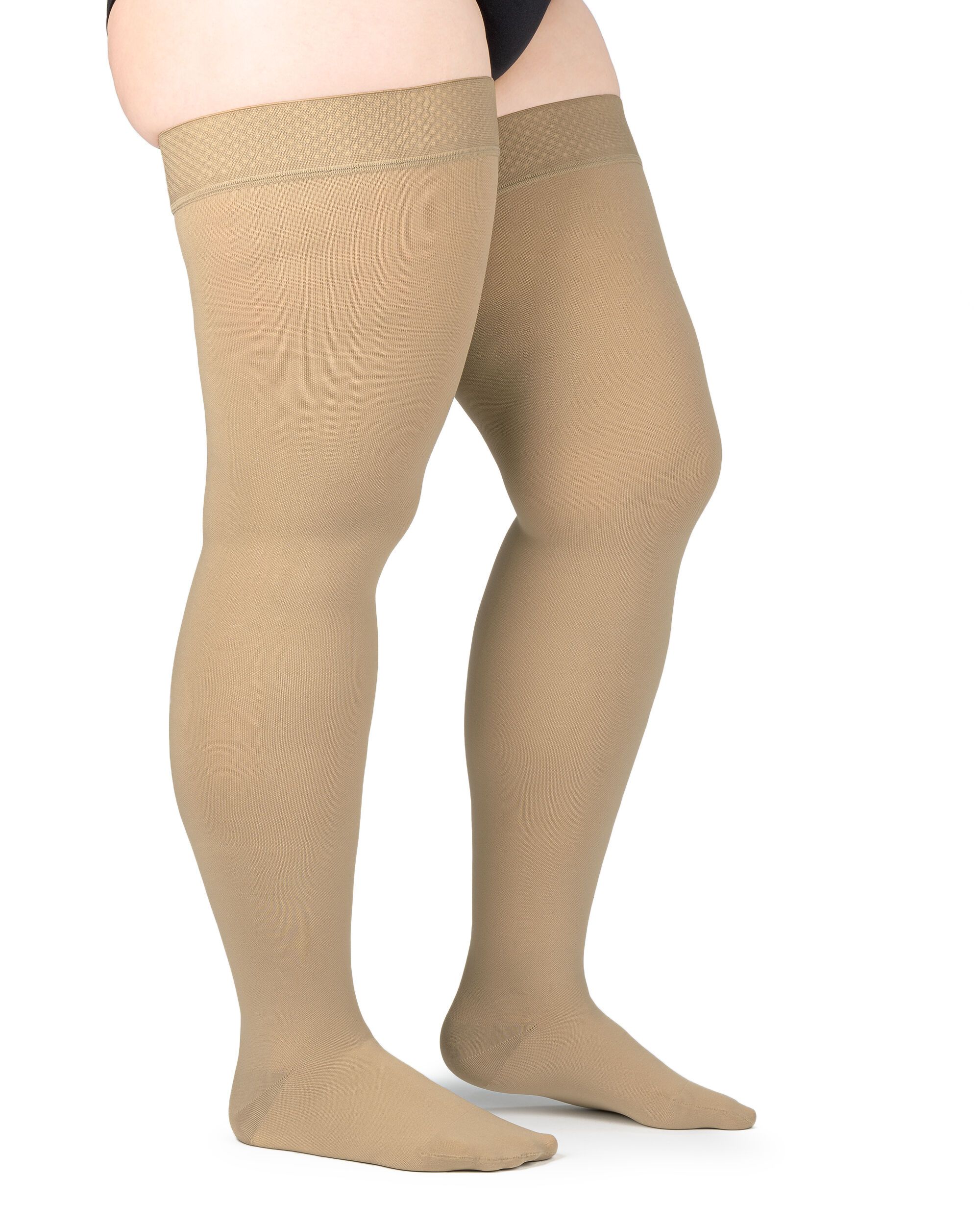 Beige Kompressions-Schenkelstrümpfe. Haftband am Oberschenkel. Blick von der Seite auf die Beine einer Person.