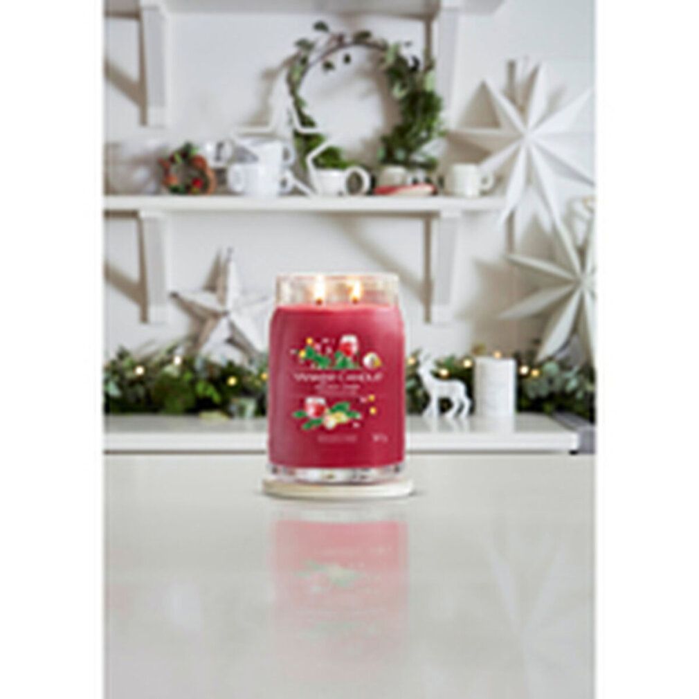 Rote Kerze mit Glasdeckel. Aufschrift: Yankee Candle Holiday Cheer. 567 g. Auf weißem Tisch.