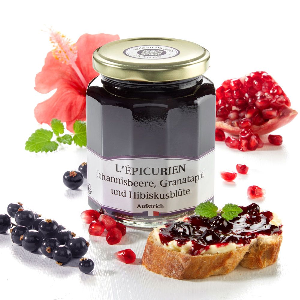Glas mit Aufstrich, Etikett mit Produktnamen. Johannisbeere, Granatapfel, Hibiskusblüte. Daneben Früchte und Brot.