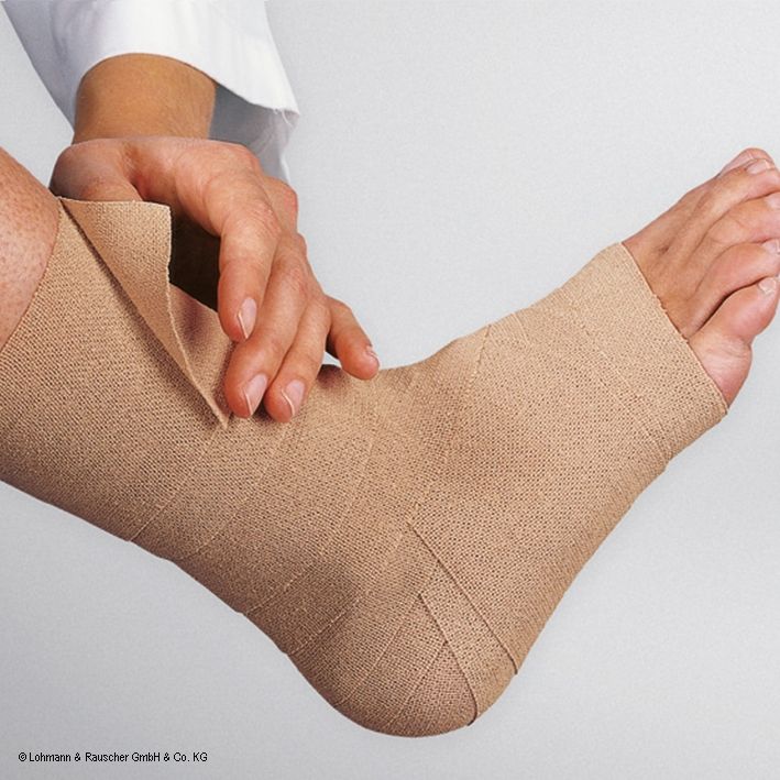 Beige Rosidal® haft Bandage am Knöchel. Eine Hand wickelt die Bandage. Text: Lohmann & Rauscher GmbH & Co. KG.