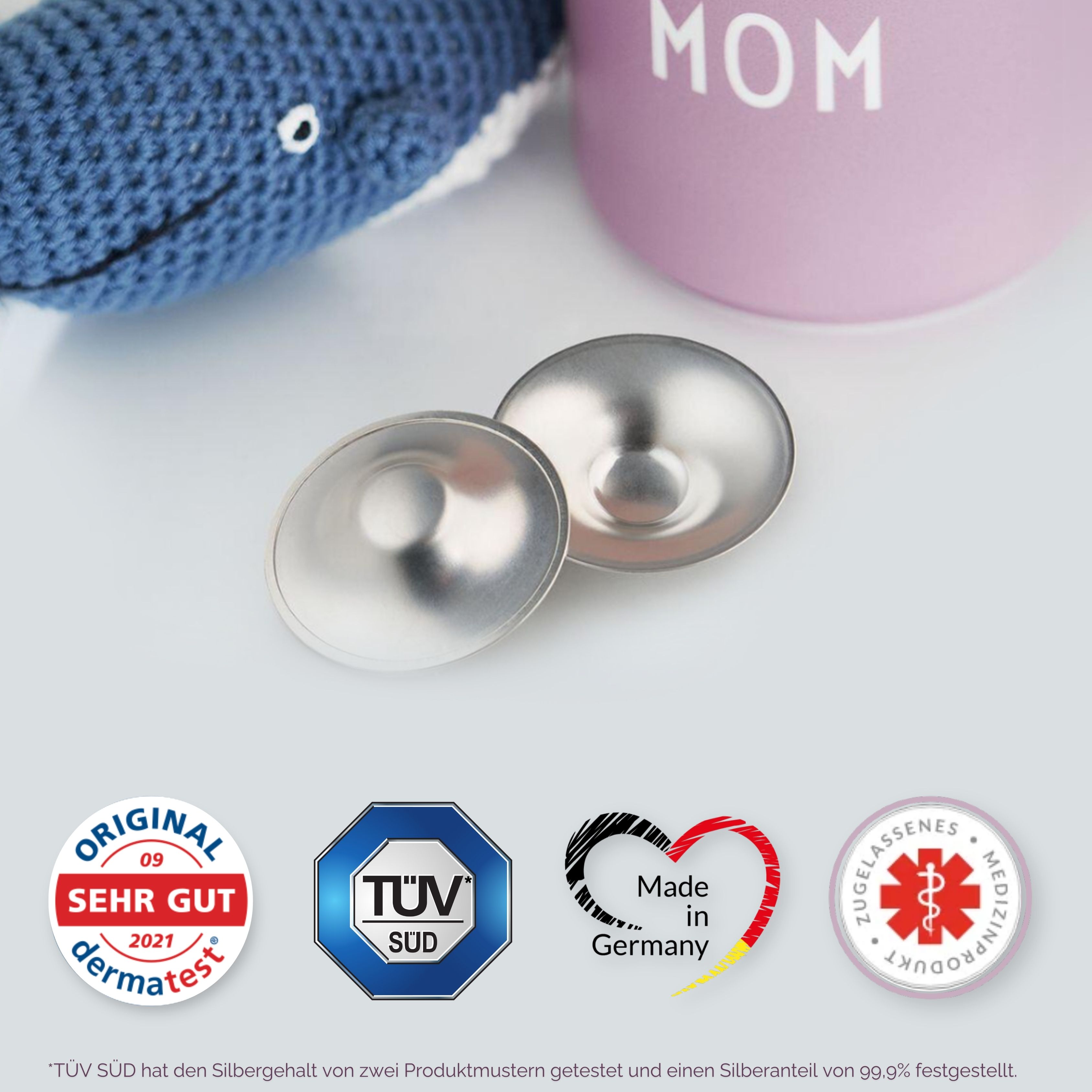 Zwei silberne Brusthütchen. Logos: "dermatest", "TÜV SÜD", "Made in Germany", und ein medizinisches Symbol.