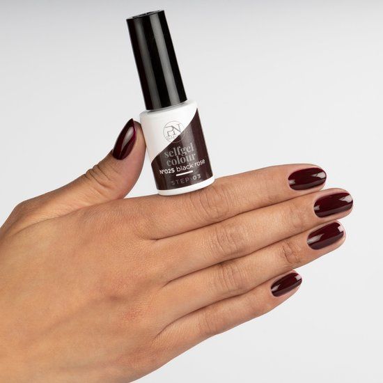 Hand mit lackierten Nägeln und Nagellackflasche. Aufschrift: selfgel colour N°025 black rose STEP 03.