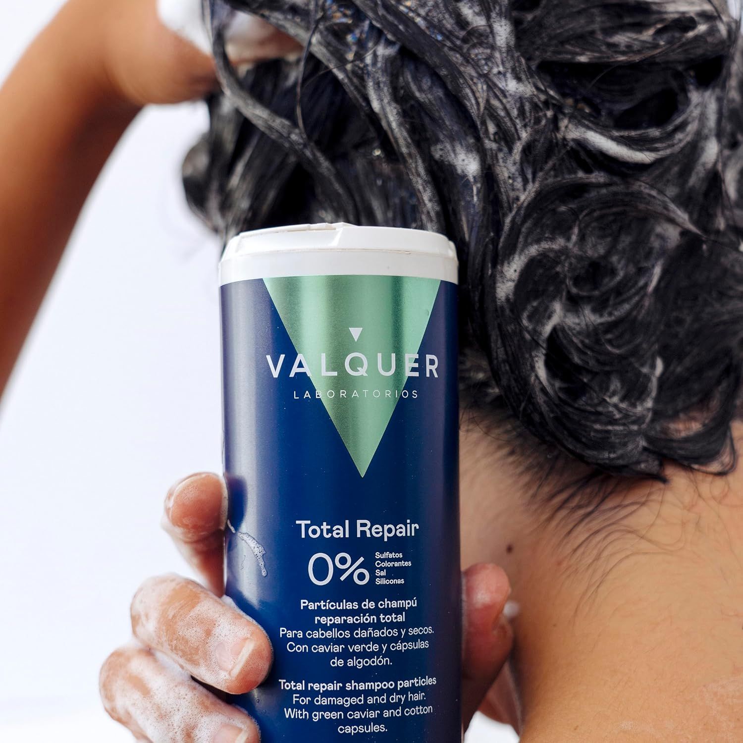 Eine Person wäscht sich die Haare mit "Total Repair" Shampoo in der Dusche.
