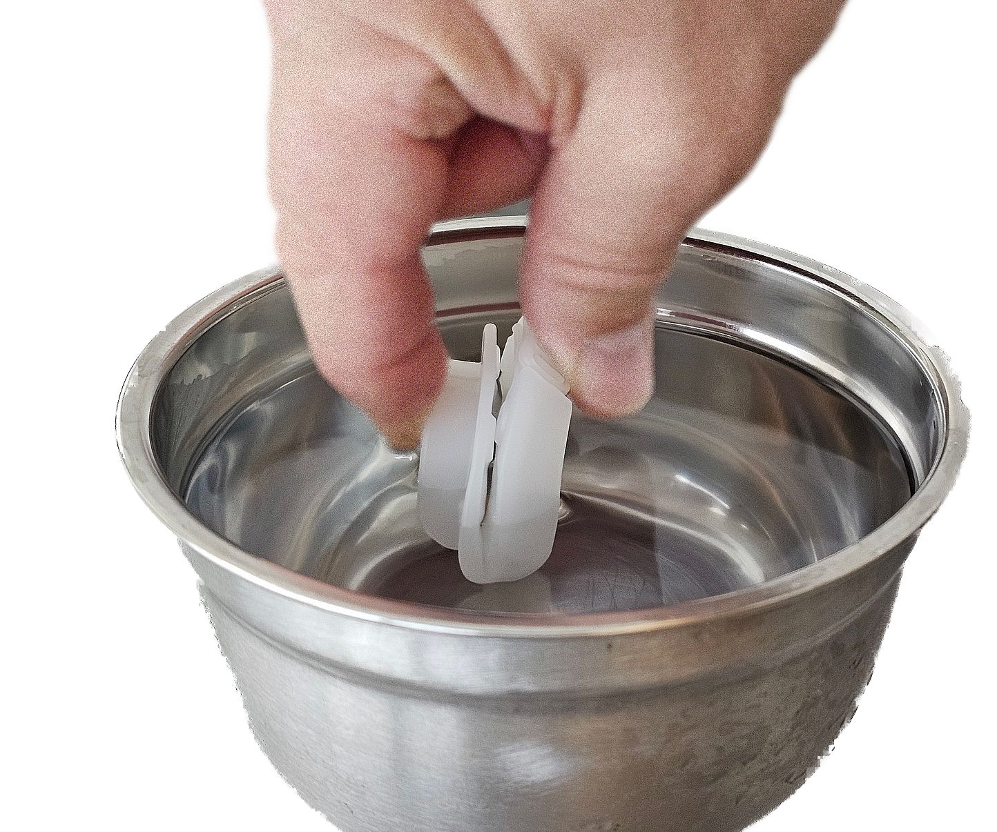 Hand legt eine weiße Zahnspange in eine Metallschüssel. Zahnspange in U-Form.