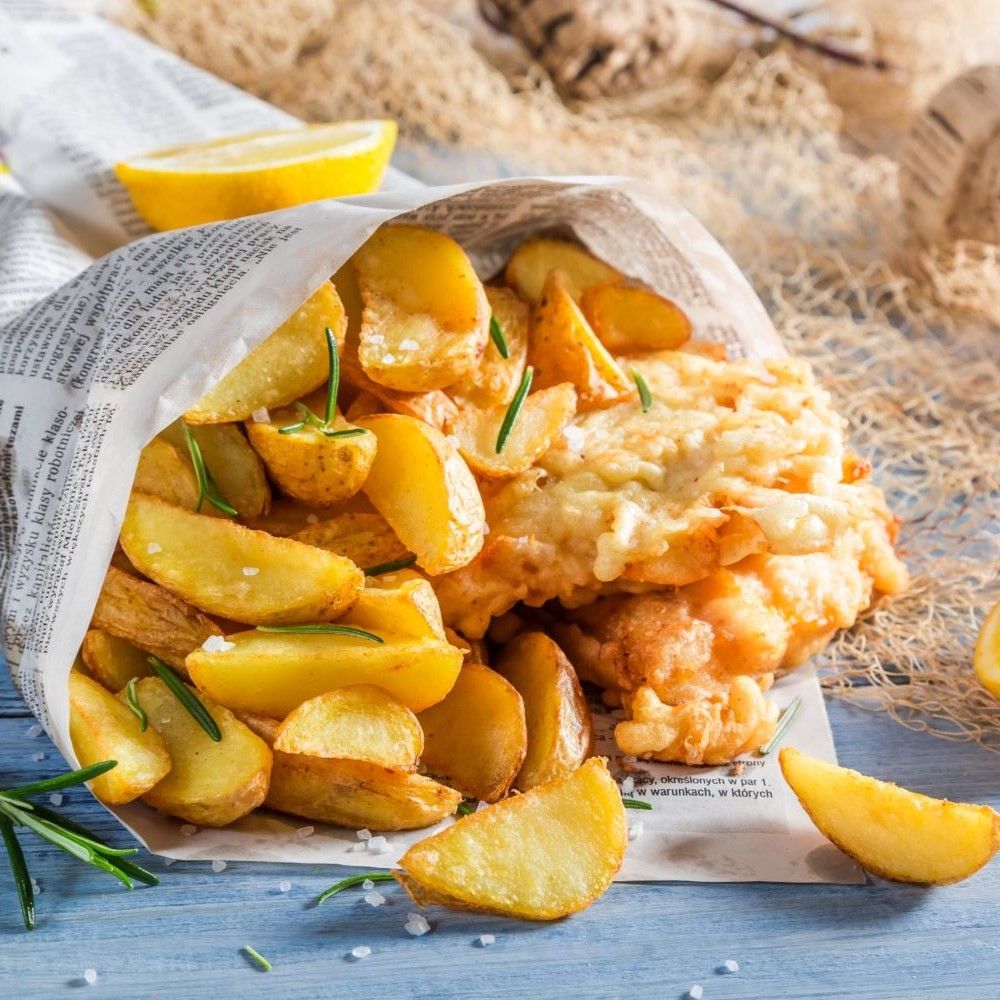 Pommes Frites und Fisch in Papiertüte. Zitrone und Rosmarin.