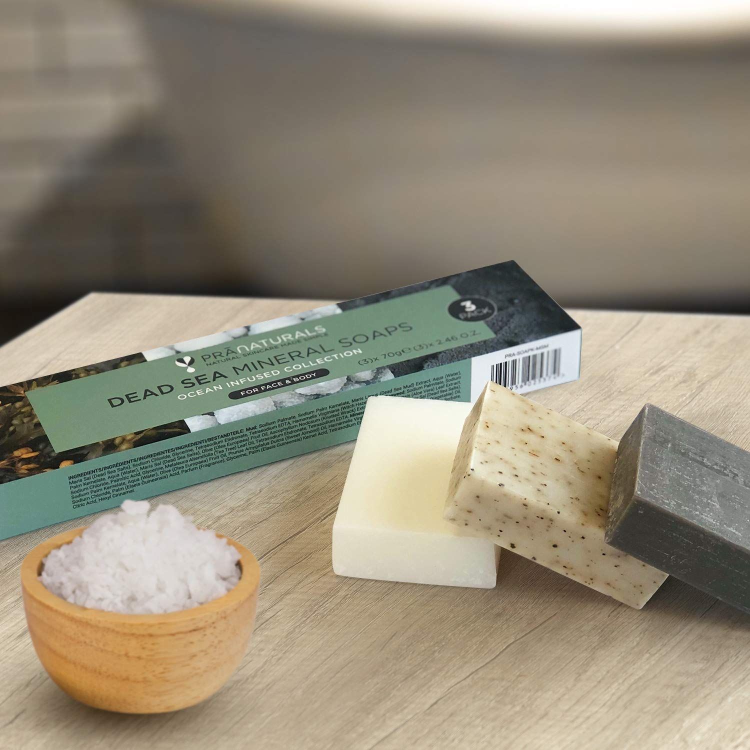 Drei Seifenstücke und eine Verpackung auf Holz. Eine Schale mit Salz.
